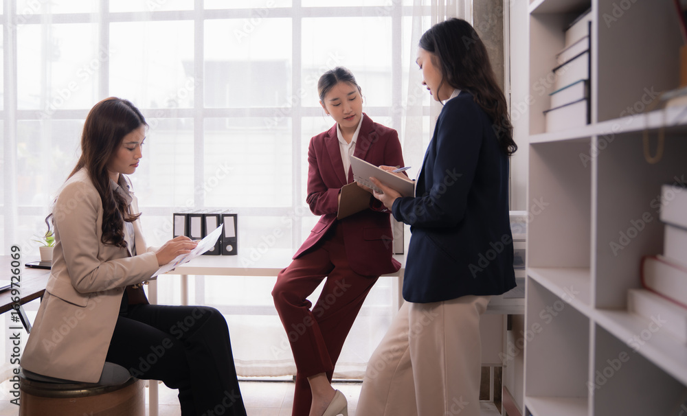 Aufkleber three asian businesswomen are discussing and working together using documents and a notebook in a mo