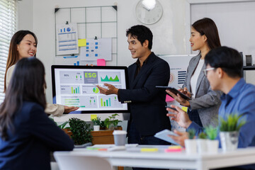 Team of asian business ESG Presentation and Team Collaboration. A professional woman presents ESG metrics to colleagues in a modern meeting room.
