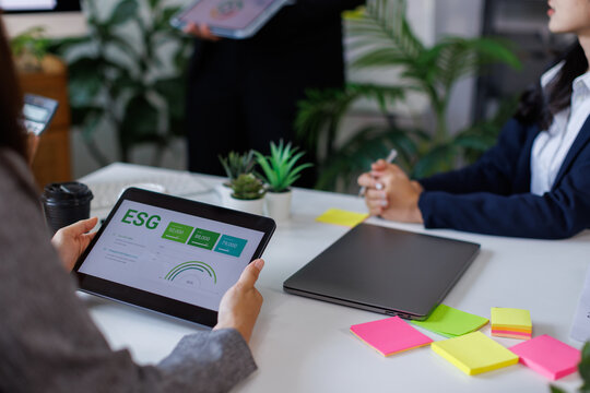 Team of asian business ESG Presentation and Team Collaboration. A professional woman presents ESG metrics to colleagues in a modern meeting room.
