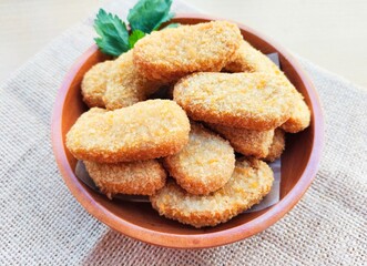 Fried chicken nuggets in a wooden plate are on the table.