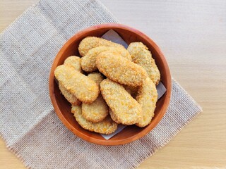 Fried chicken nuggets in a wooden plate are on the table. Top of view. 