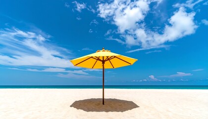 A vibrant yellow beach umbrella casts a shadow on the pristine white sand, bathed in the bright sunlight of a beautiful, cloud-filled blue sky.