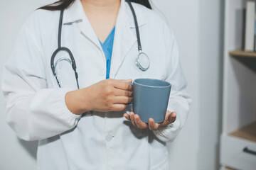 Portrait of Asian doctor woman standing holding coffee cup in white studio background