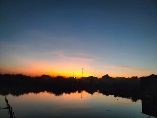 Beautiful sunrise over a calm river with colorful sky reflecting on the water, creating a peaceful and serene landscape.