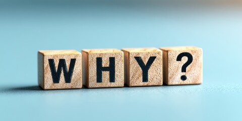 The wooden blocks spelling WHY with question mark on blue background