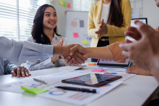 Meeting, partnership and asian business people shaking hands in the office for a deal, professional and employees with handshake for agreement, welcome or greeting.
