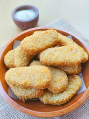 Fried chicken nuggets in a wooden plate and mayonnaise sauce in a small wooden bowl on the table.