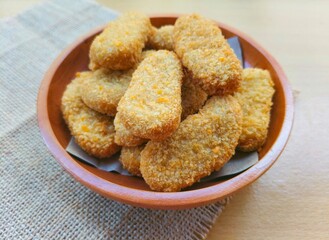 Fried chicken nuggets in a wooden plate on the table.