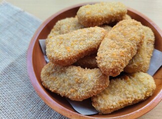 Fried chicken nuggets in a wooden plate on the table.