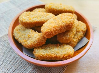 Fried chicken nuggets in a wooden plate on the table.
