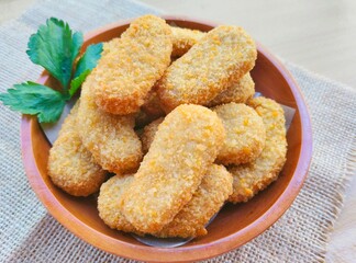 Fried chicken nuggets in a wooden plate on the table.