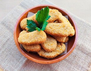 Fried chicken nuggets in a wooden plate on the table.