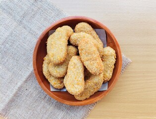 Fried chicken nuggets in a wooden plate on the table.