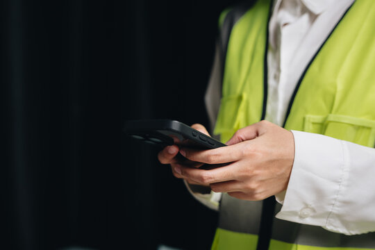 Construction Worker in Safety Vest Using Smartphone for Communication and Project Management
