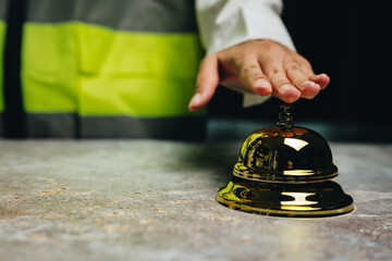 Hand Pressing Gold Reception Bell on Marble Counter in Modern Service Environment