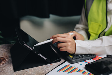 Professional hands using tablet and calculator for financial analysis in modern office environment