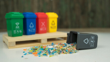 Microplastic granules spilled from a small bin, representing the global micro plastics pollution crisis and recycling challenges. Conceptual photo.