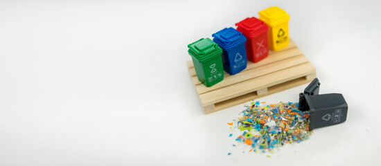 Microplastic granules spilled from a small bin, representing the global micro plastics pollution crisis and recycling challenges. Conceptual photo.