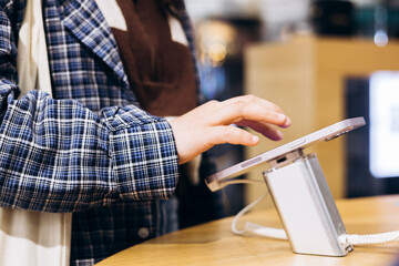 Hand touching screen of tablet display at store, close-up of modern technology.