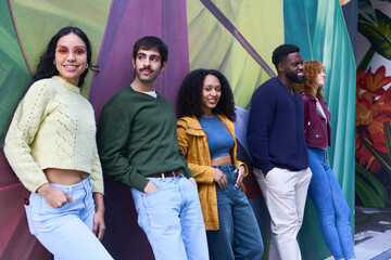 Group of young creative people leaning against a colorful mural © Oscar