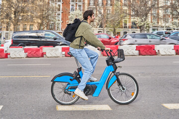 Student riding public bike sharing service in urban setting