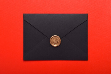 Black envelope with wax seal isolated on red background