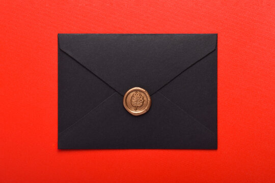 Black envelope with wax seal isolated on red background