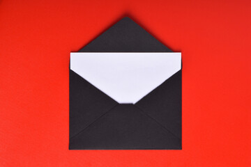 Opened black paper envelope with paper sheet isolated on red background