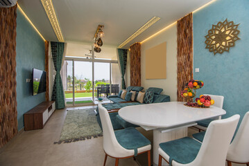 Living room lounge area in luxury apartment show home showing interior design decor furnishing with patio terrace and pool view