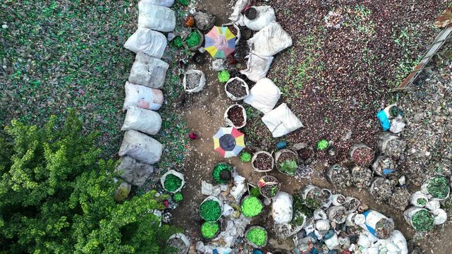 Bogura, Bangladesh - 20 August 2025: Aerial view of piles of green and brown glass, sorted into bags, creating a textured mosaic of colors and recycled materials.