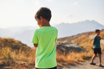 Boy in bright green shirt outdoors in mountain landscape
