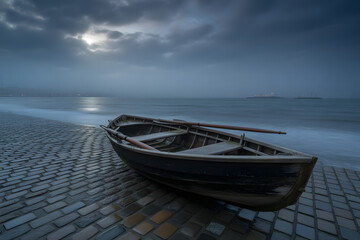 Naklejka premium Rowboat on a cobblestone beach under a cloudy sky wooden boat