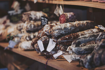 Artisan meats carefully arranged on wooden shelves in a rustic charcuterie shop during a cozy...