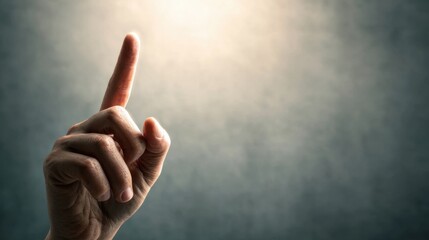 A hand with a pointed finger gestures upwards against a softly lit background, suggesting emphasis or a call to attention.
