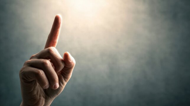 A hand with a pointed finger gestures upwards against a softly lit background, suggesting emphasis or a call to attention. - Powered by Adobe