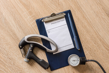 Doctor's clipboard with modern hand expander and stethoscope on table, top view, flat lay. Hand...