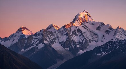 Fototapeta premium Majestic snow-capped peaks rise against a vibrant sunset sky, showcasing a breathtaking mountain range.