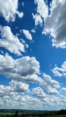 Obraz premium Vibrant blue sky with fluffy white clouds over a picturesque landscape