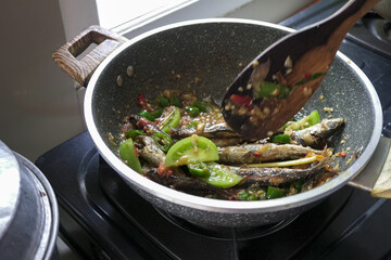 A woman's hand puts green tomatoes into a dish.