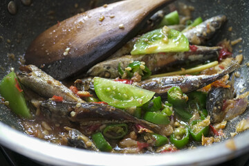 A woman's hand puts green tomatoes into a dish.
