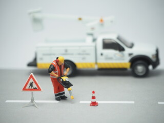 Miniature toy and unfocus mini car with blurred background. Road maintenance conceptual design.
