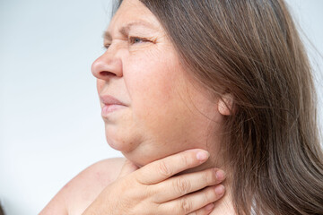 Obraz premium Adult woman indicating health problem in throat area, Female with neck pain, sore throat, emotional strain, health issue, seasonal illness, Symptoms infection