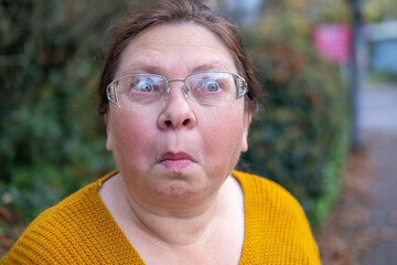 Surprised, Shocked middle-aged woman with long hair outdoors, portrait shocked terrified adult...