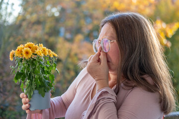 mature woman and autumn flowers, sensitivity to pollen, Allergy awareness, emotional wellbeing, and...