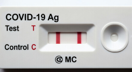 Close-up of a positive COVID-19 antigen test showing two red lines, indicating a detected infection.