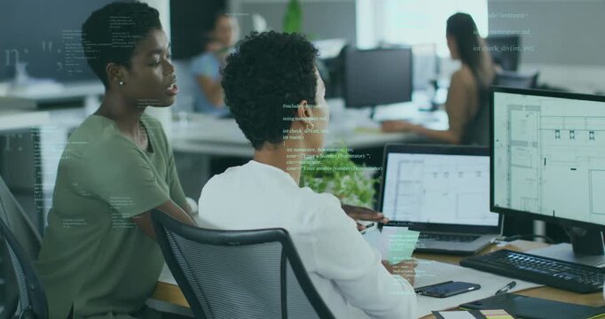 Developer scrolling code grabbing sticky notes while designer guiding cursor on grid in tech office