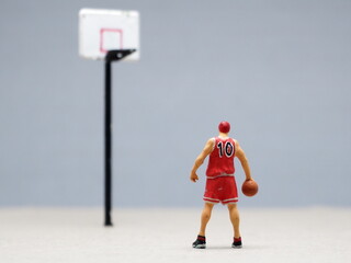 Mini toy of action figure at table with blurred background. Macro toy photography concept design. Minifigure of basketball player character at basketcourt.	