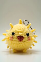 keychain of A chubby crochet pufferfish with light yellow yarn spikes and a surprised face.