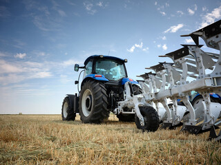 Rear view of a large tractor with a knife plow in a field. Start tillage after harvest.