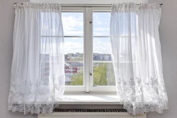 White lace curtains framing a window with city view